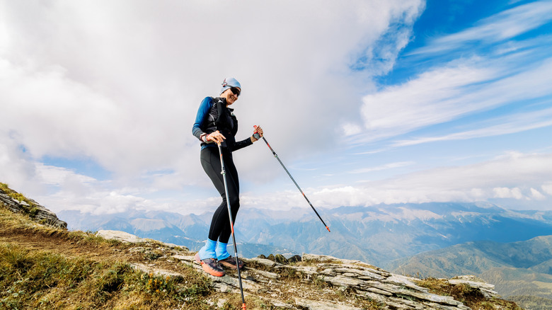 happy hiker coming downhill in the mountains with trekking poles