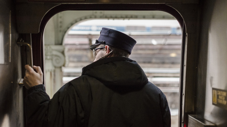An Amtrak crew member peers through an open doorway