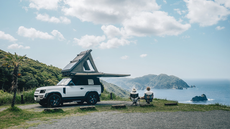 couple sitting in chairs next to car with overlanding setup enjoying view