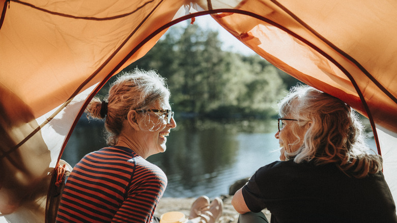 Two senior women sitting in tent at campsite