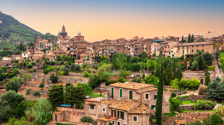 A hilltop stone village surrounded by green hills and trees
