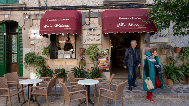 An older couple walking out of a local bakery in Europe