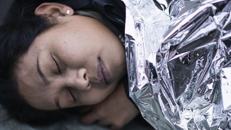 Close-up of camper sleeping wrapped in a foil blanket
