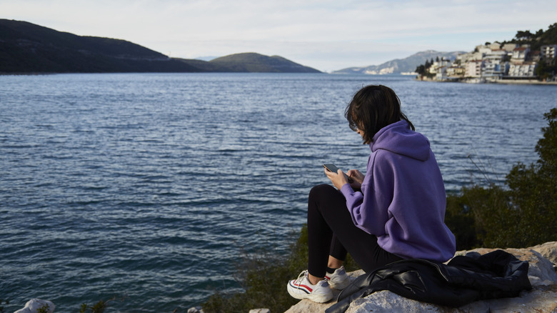 A woman sits on a rock by the water in Neum