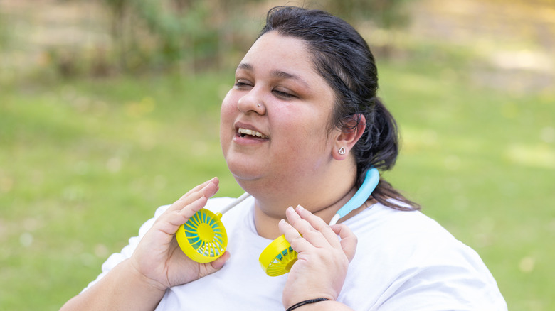 Woman using a neck fan to cool down