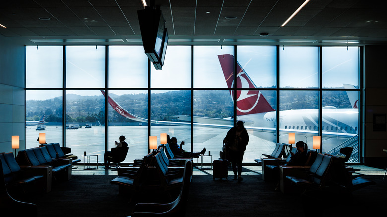 travelers waiting in a lounge with floor-to-ceiling windows at San Francisco International Airport