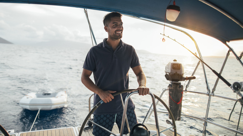 Smiling young man as helmsman on sailboat