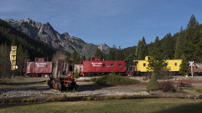 Train cars and a motel sign in front of mountains at Jubilee Rail Resort, aka Dunsmuir's train hotel, in California