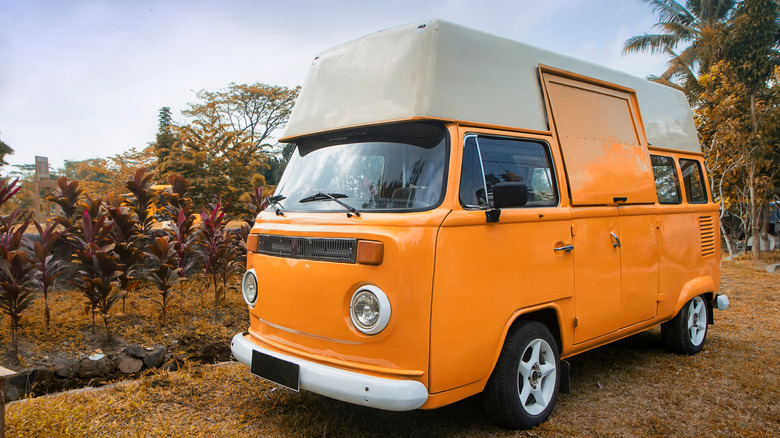 vintage orange camper van parked next to plants