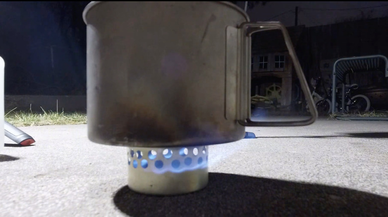 A small pot on a cat food can stove.
