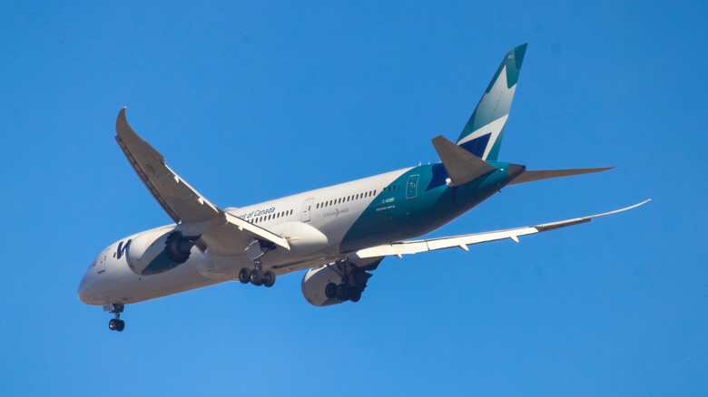 Boeing 787 Dreamliner airplane, with landing gear extended, flying against a pristine blue sky