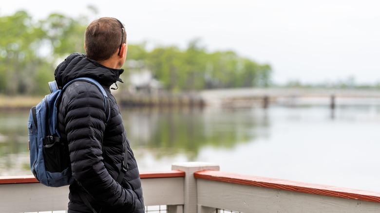 man with backpack looking at view of bridge