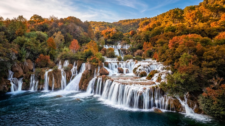 Waterfalls leading into a lake surrounded by colorful fall trees