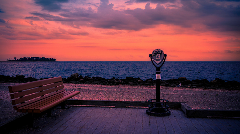 A bench and viewfinder stand near the water at sunset in Milford, Connecticut