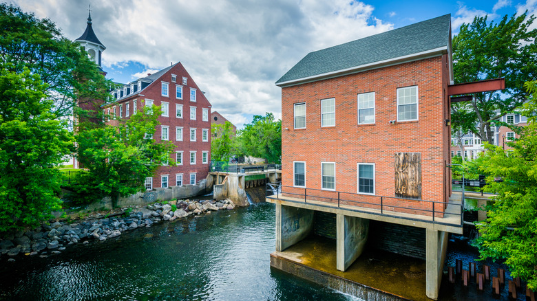 Historic brick buildings stand on the edge of a river in downtown Laconia, New Hampshire