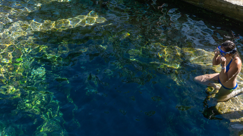 A girl adjusts her goggles as she prepares for a dive down Jacob's Well, a popular local swimming hole near Austin