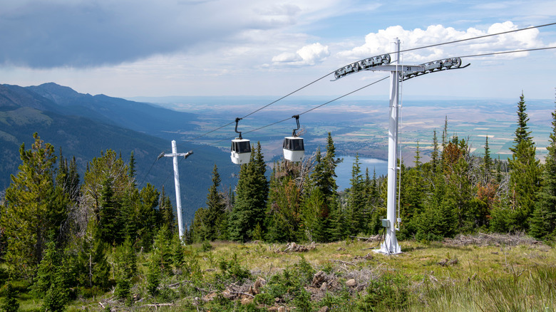 gondola cars coming up a hill, mountains in distance