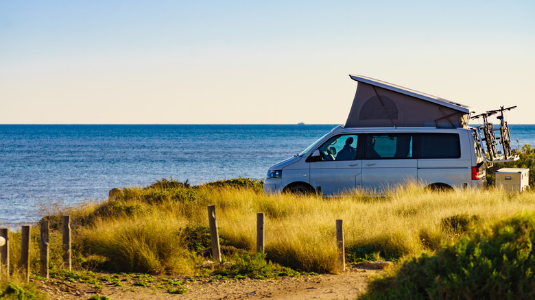 camper van with top tent and bikes parked by the ocean