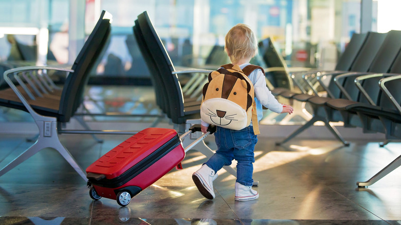 A small child pulling a suitcase in the airport.
