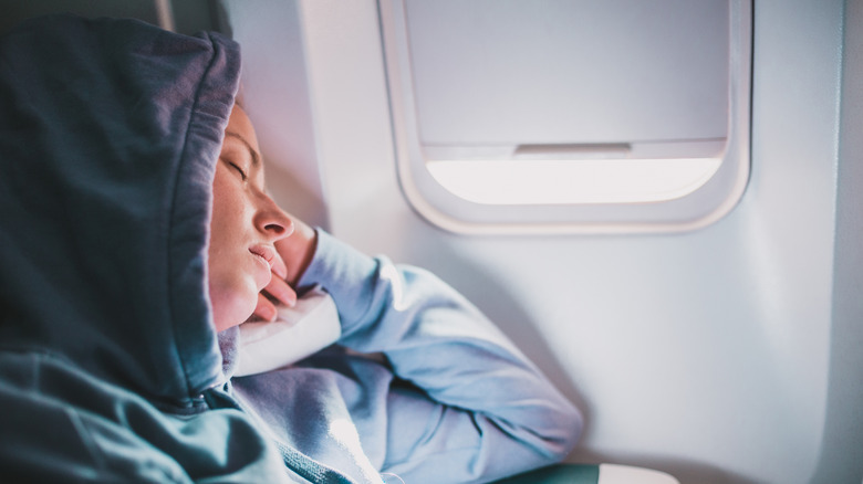 A woman sleeping uncomfotably on a plane