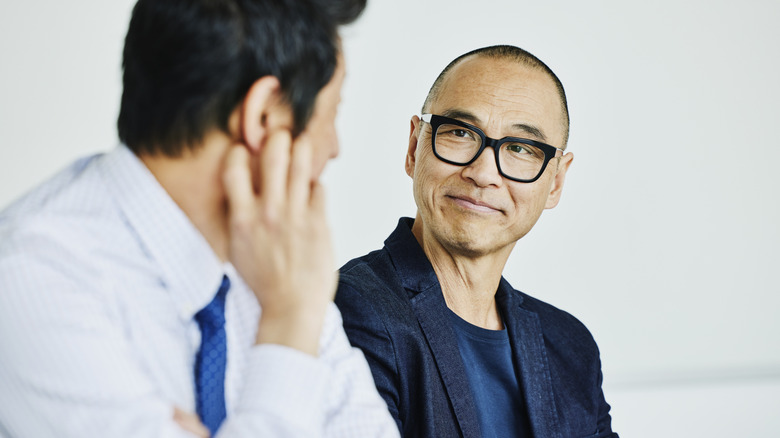 Two men converse closely to each other
