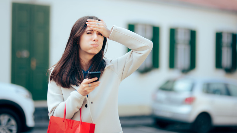 Confused looking woman on street holding phone