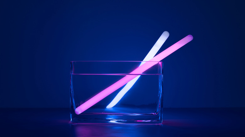 Two glow sticks rest in a glass vessel