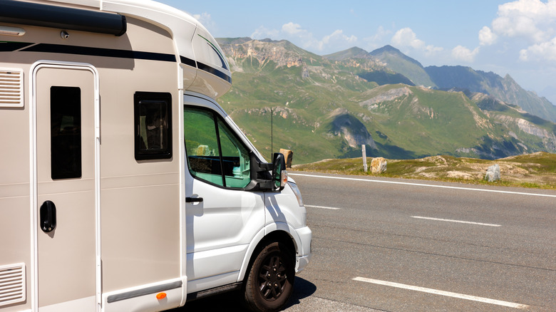 An RV camper van on the road with a mountain view.