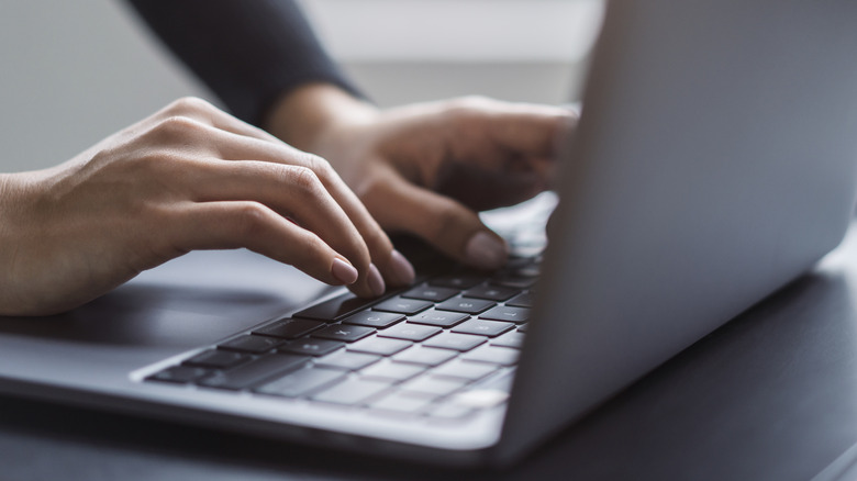 person's hands typing on a laptop