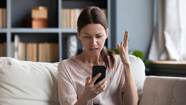 confused woman looking unhappy looking at her phone screen