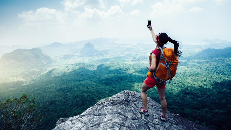 Hiker at the top of a mountain taking a photo