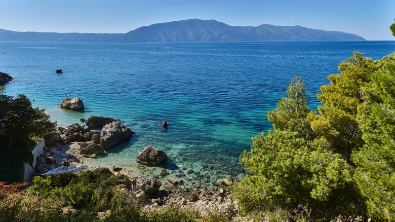 Aerial view of a beach with clear water and mountains in the background
