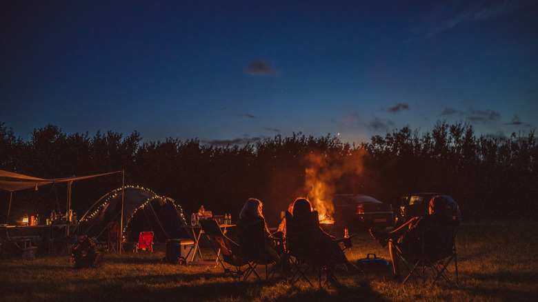 group of people relaxing around a campfire at night