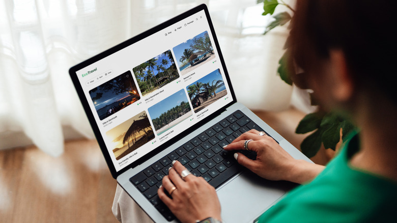 A woman using a laptop to check traveling platforms.