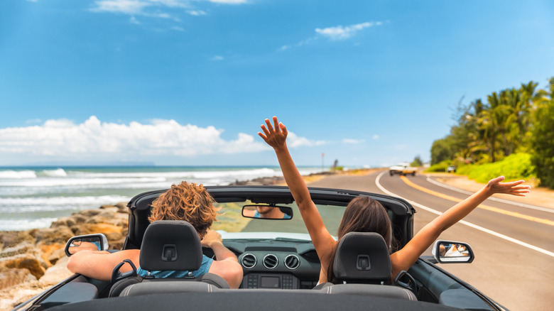 a couple in a convertible car on a coastal road