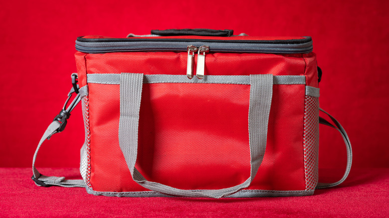 A red lunch bag cooler tote sitting on a red backdrop