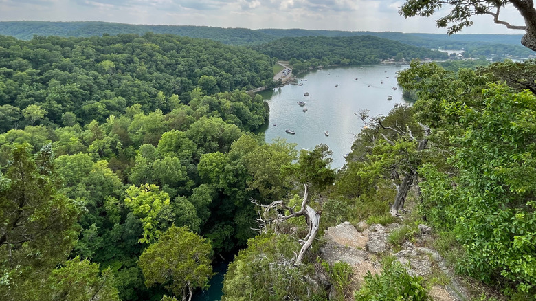 Overhead view of green forests and a lake in the ozarks dotted with boats