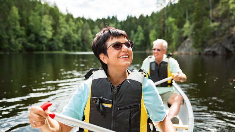 A couple kayaking a forest-lined lake in Finland