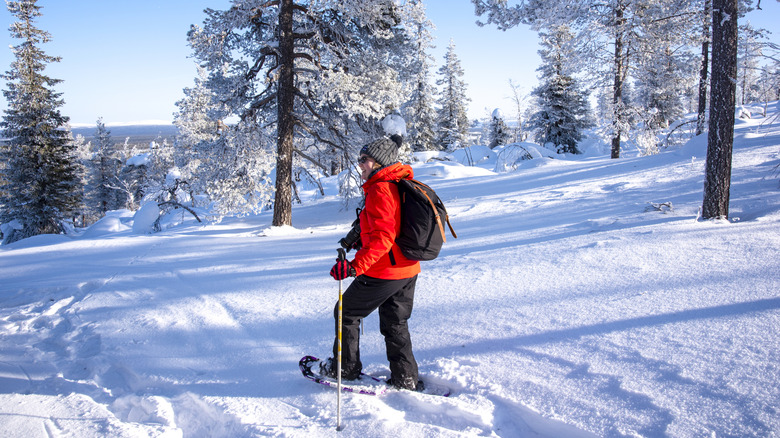 A woman snowshoeing with white trees behind her