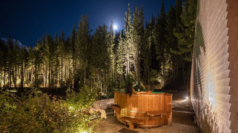 A couple toasting while in a jacuzzi surrounded by a pine forest at Euphoria Retreat