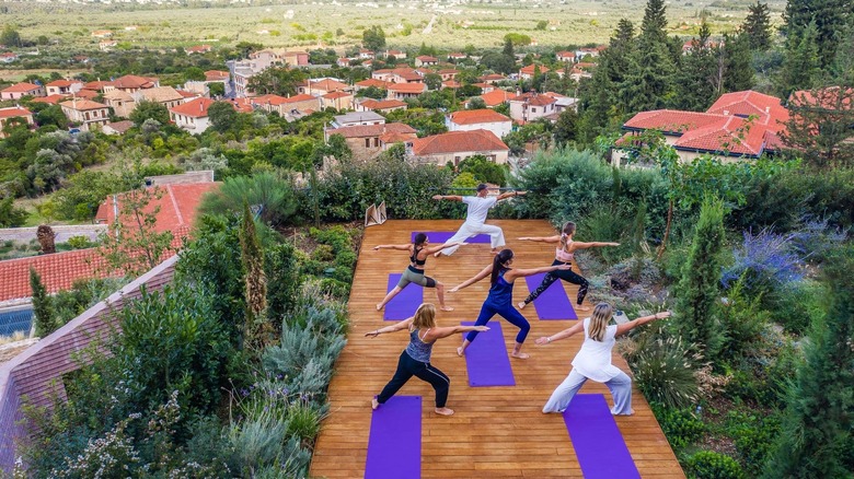 An aerial view of a yoga class overlooking the red roofs of Mystras