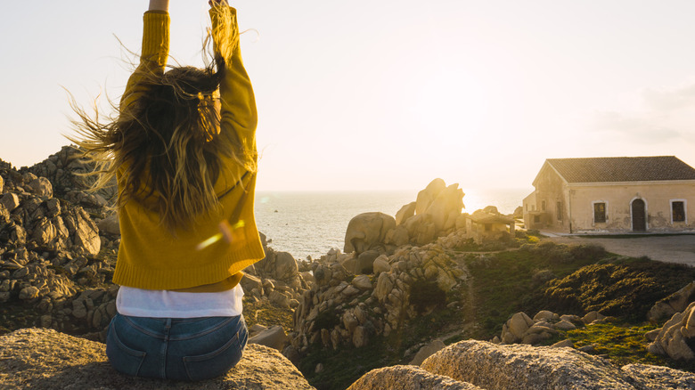 A woman stretches before a coastal sunrise in Sardinia
