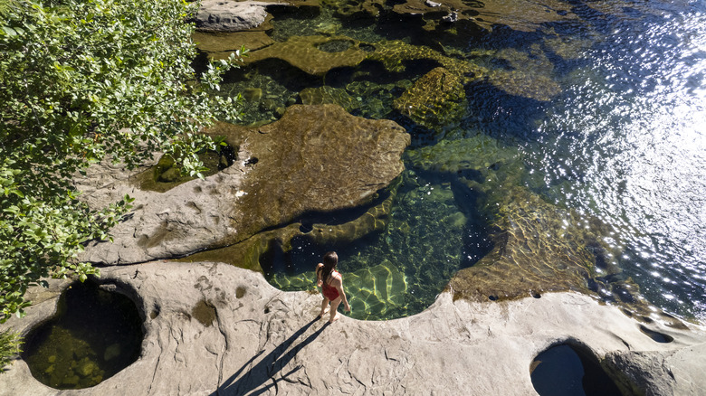 A woman standing at the banks of a swimming hole