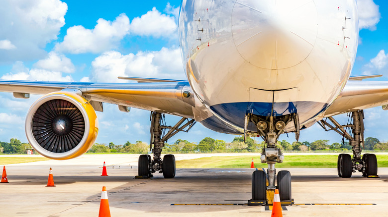 A plane close up at the airport with blue sky and clouds.