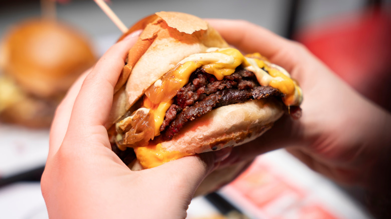 Hands clutch a smash burger