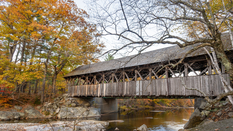 wooden covered bridge over creek, trees with fall foliage