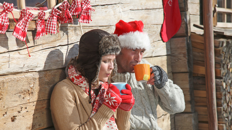 couple enjoying hot drink outside of a cabin