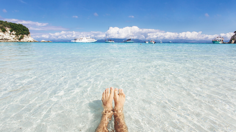 two feet floating on crystalline water on the beach