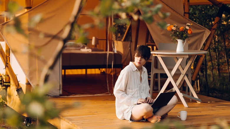 Woman on laptop while glamping