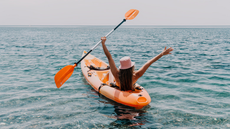 Woman in a kayak with her arms in the air